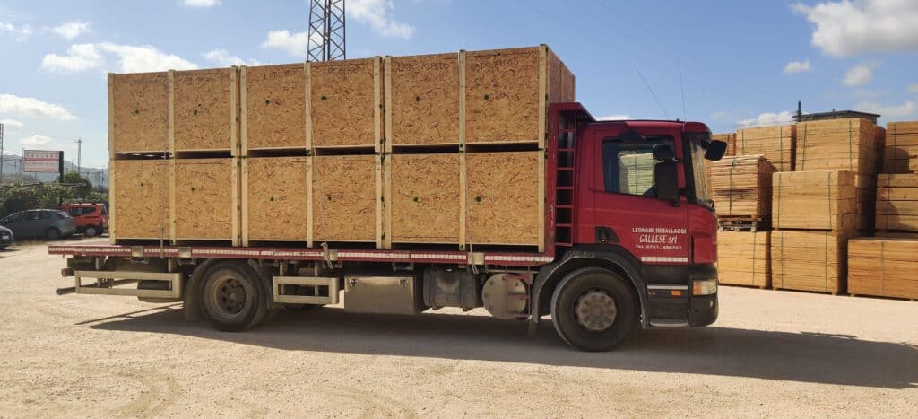 Camion rosso con casse di legno su rimorchio.