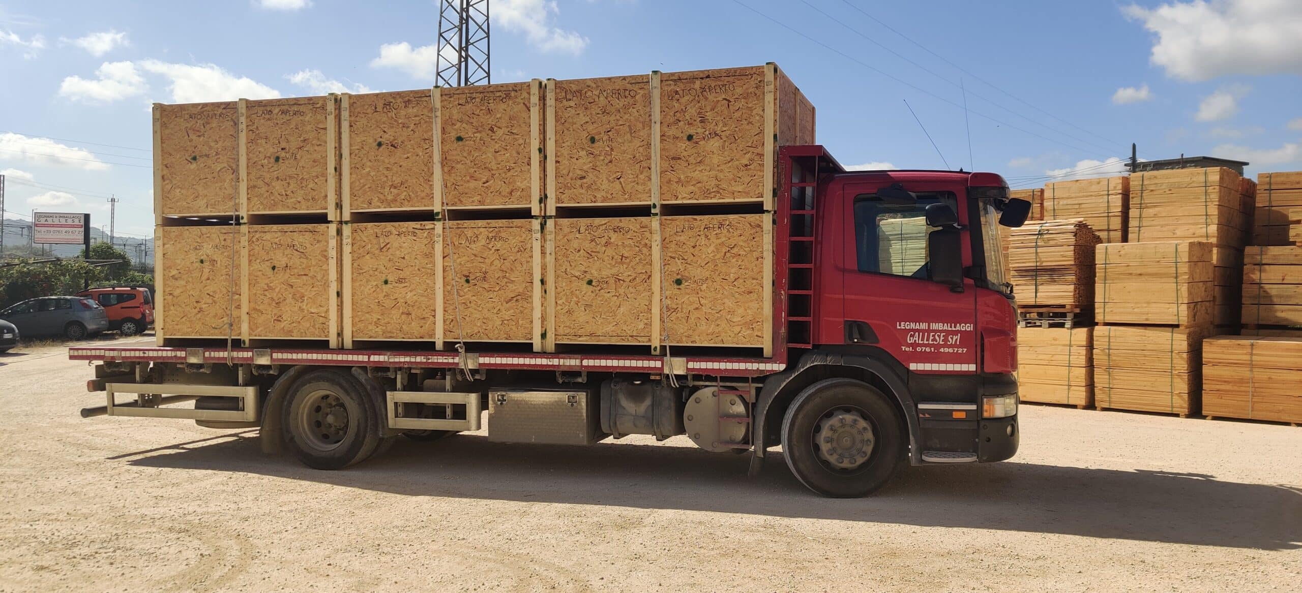 Camion rosso con casse di legno su rimorchio.