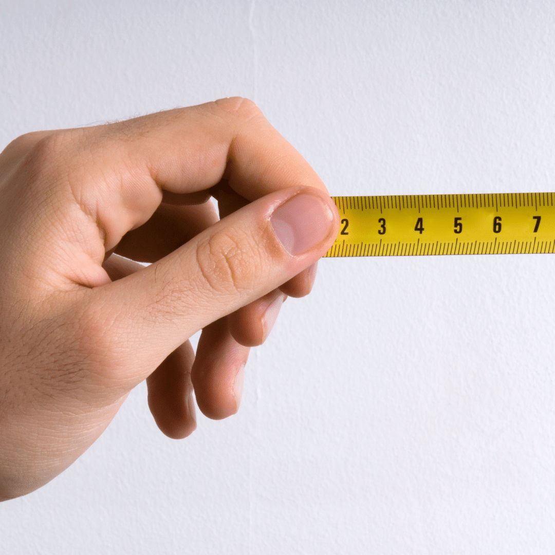 Mano che tiene un metro a nastro giallo.