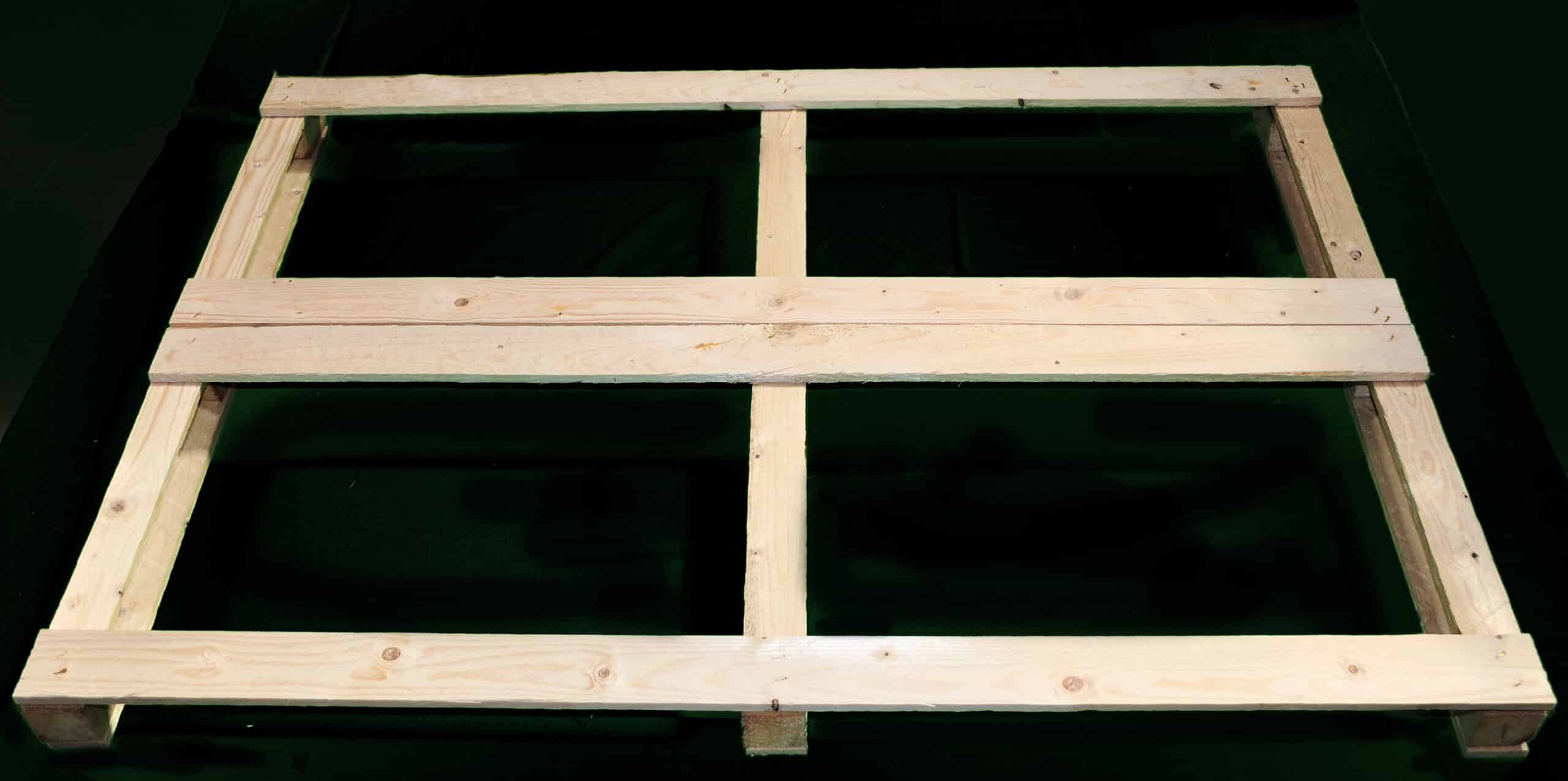 Struttura rettangolare in legno su sfondo nero.